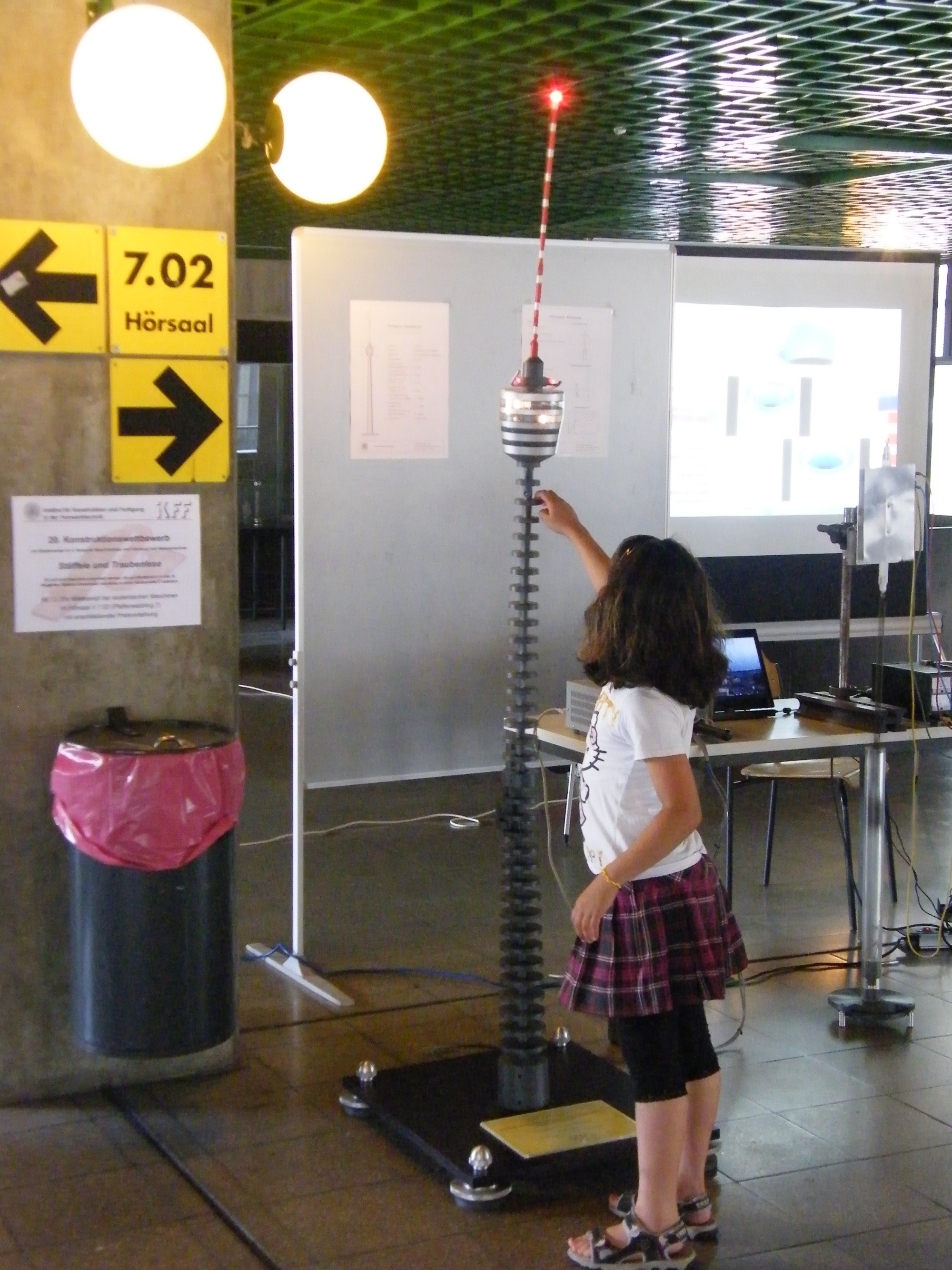 Schwingungsmodell des Stuttgarter Fernsehturms mit interessierter Besucherin am  Tag der Wissenschaft 2012